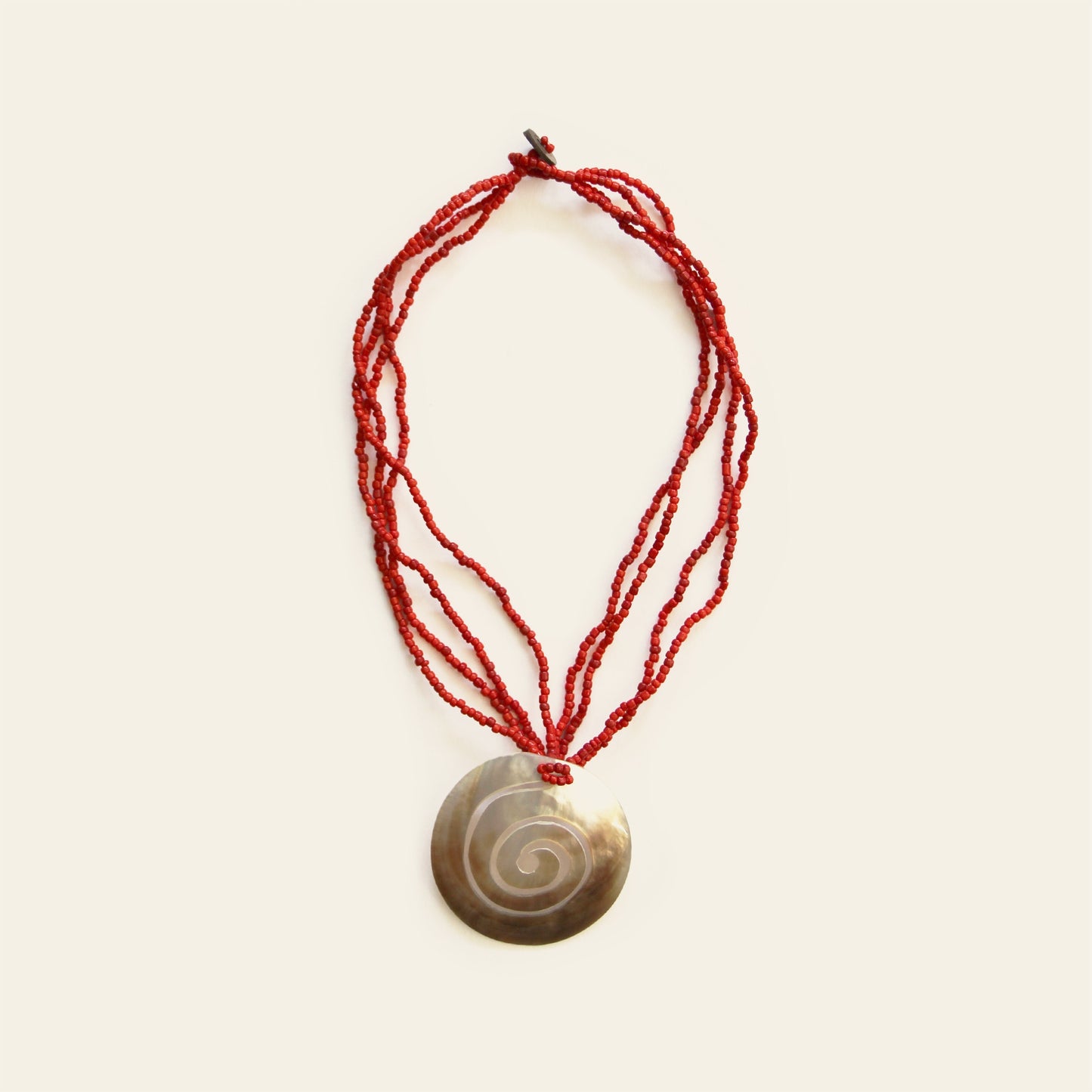 Full view of mother-of-pearl spiral pendant necklace with layered red seed beads – Nayabijou.