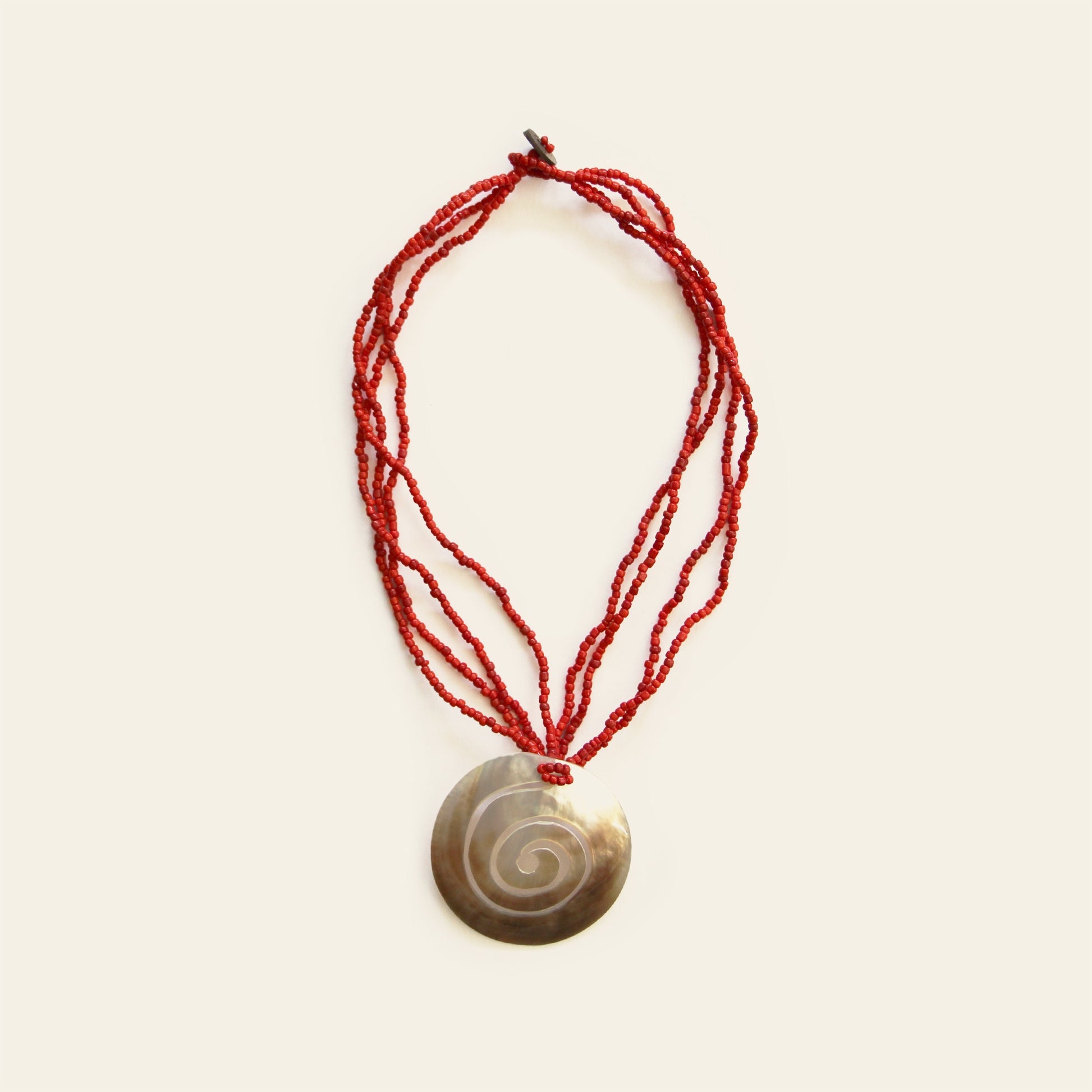 Full view of mother-of-pearl spiral pendant necklace with layered red seed beads – Nayabijou.
