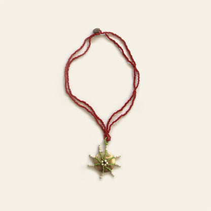 Full view of Starburst Shell Necklace with red beads and round mother of pearl pendant