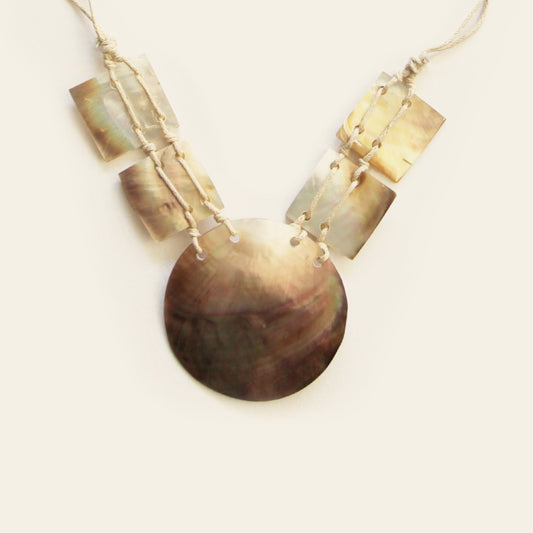 Close-up of round and square mother-of-pearl shell elements on beige cord necklace – Nayabijou.