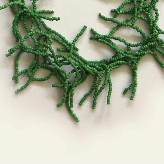 Close-up of intricate green seed bead branches on handcrafted necklace