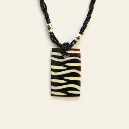 Closeup of rectangular zebra-pattern pendant necklace with black seed beads – Nayabijou.
