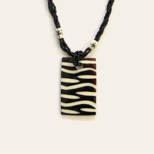 Closeup of rectangular zebra-pattern pendant necklace with black seed beads – Nayabijou.